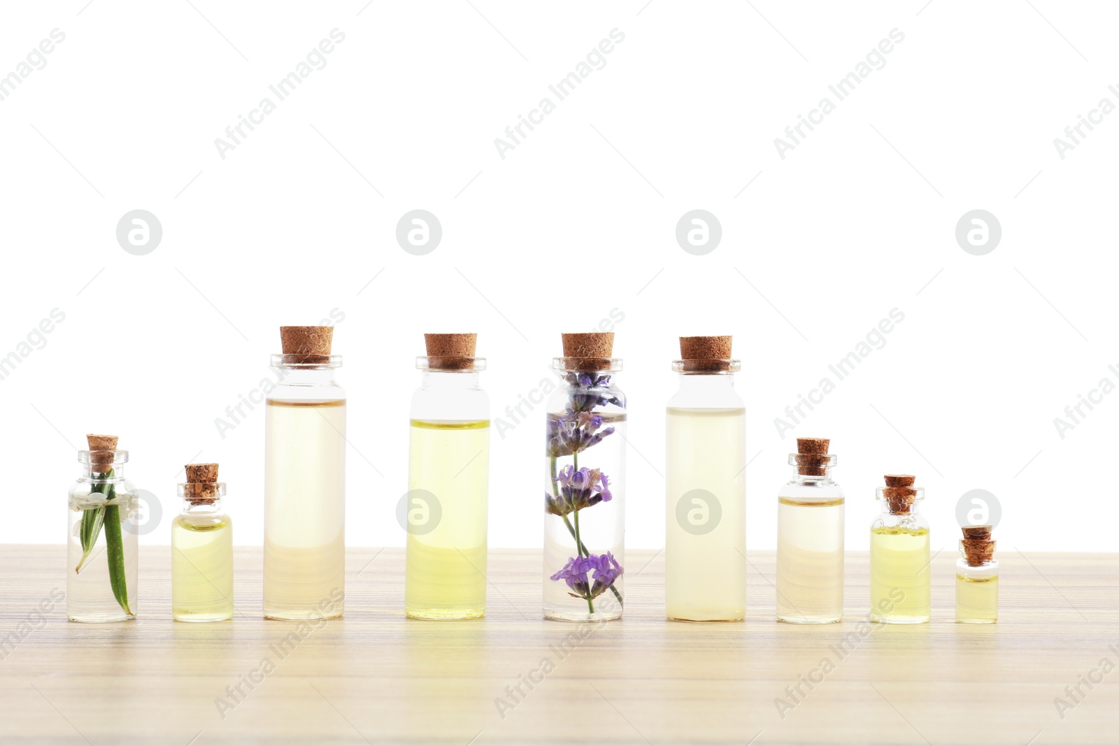 Photo of Bottles of essential oils with herbs on wooden table against white background