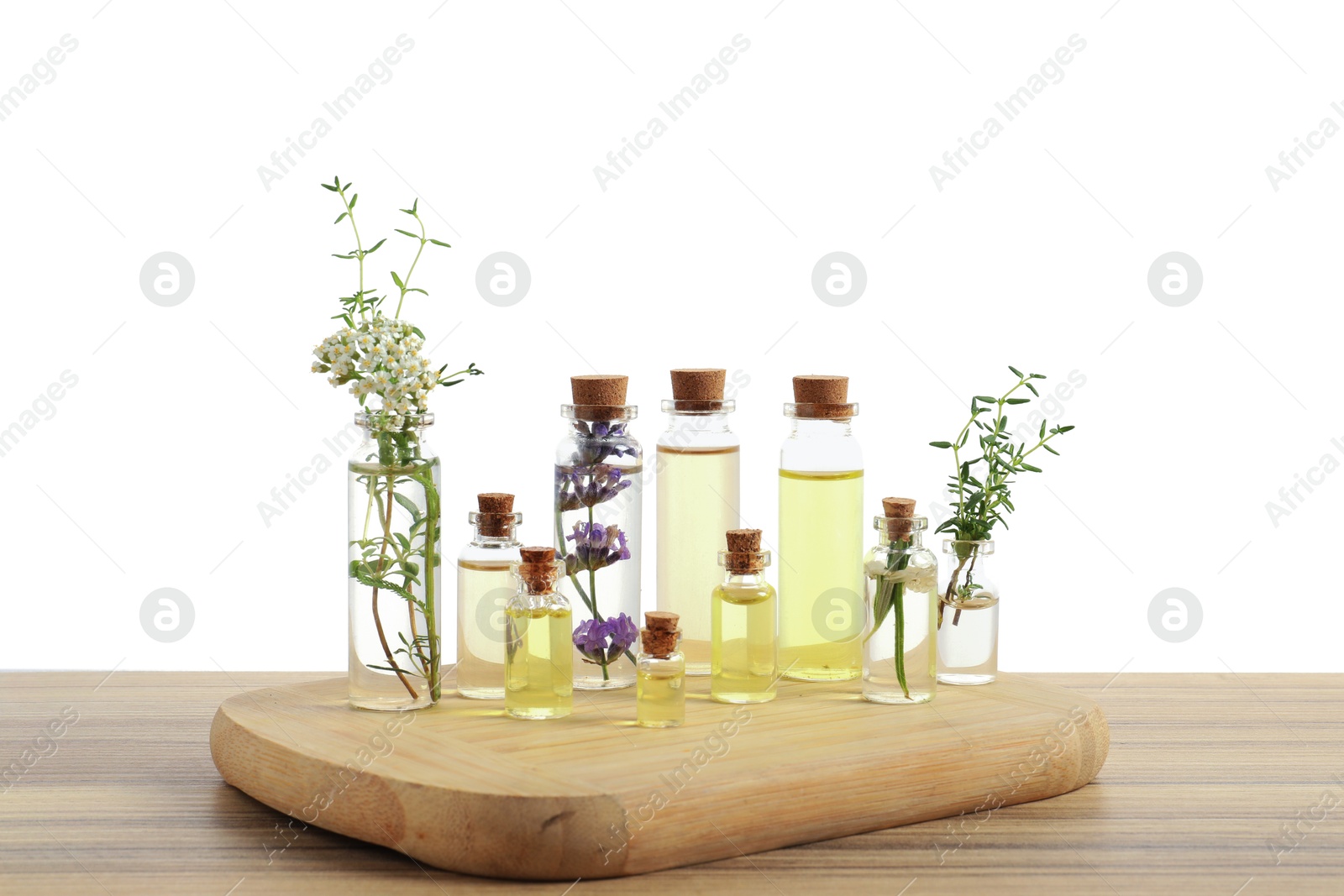 Bottles of essential oils and different herbs on wooden table against white background Photo of Bottles of essential oils and different herbs on wooden table against white background