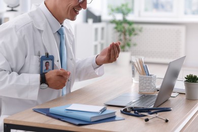 Photo of Telemedicine. Doctor having video call with patient via laptop indoors, closeup