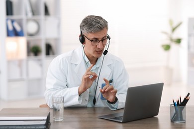 Photo of Telemedicine. Doctor having video call with patient via laptop indoors