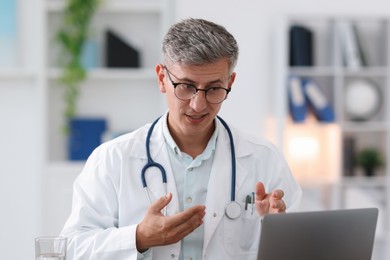 Photo of Telemedicine. Doctor having video call with patient via laptop indoors