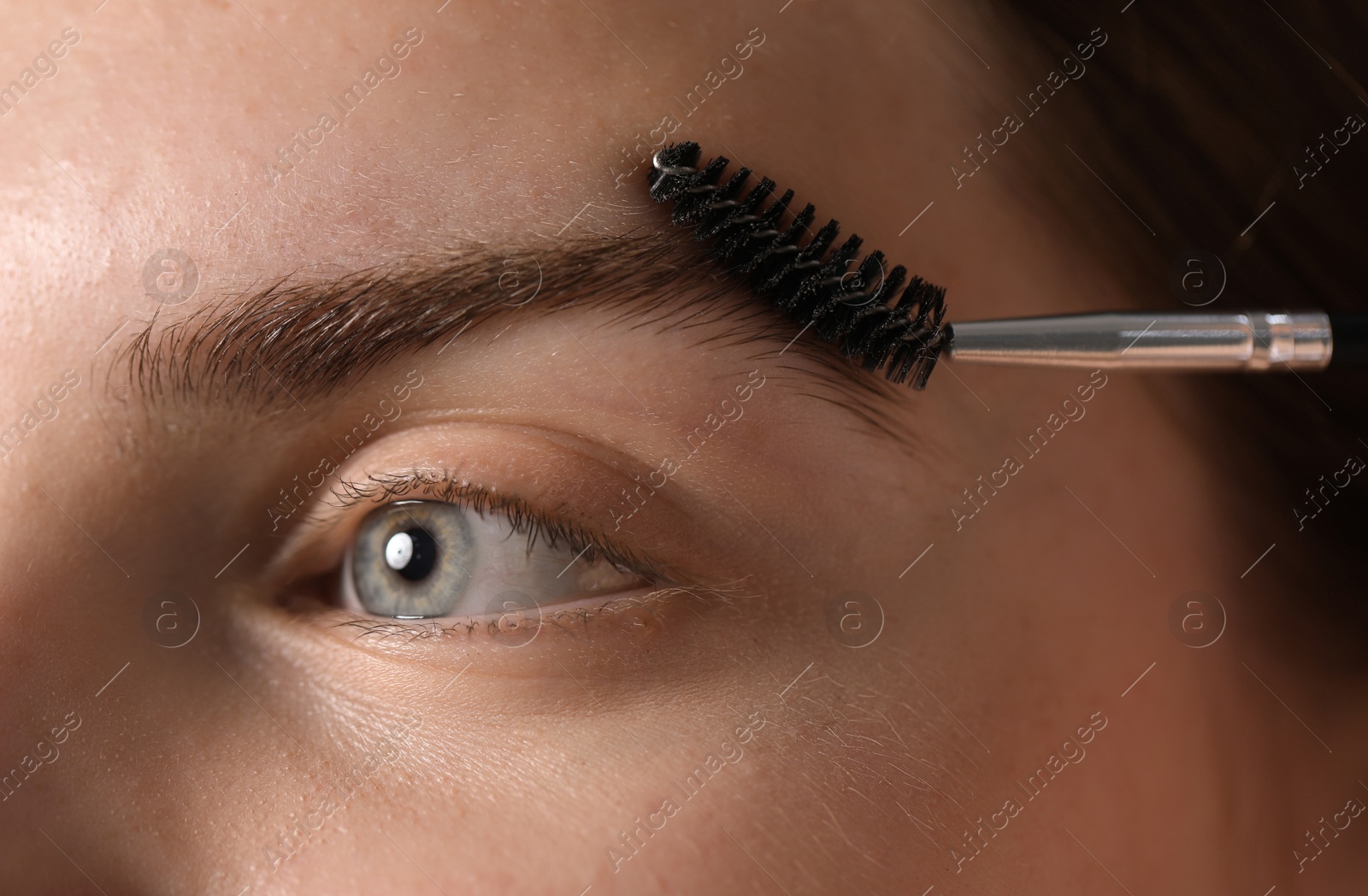 Young woman brushing her eyebrow with spoolie, closeup Photo of Young woman brushing her eyebrow with spoolie, closeup