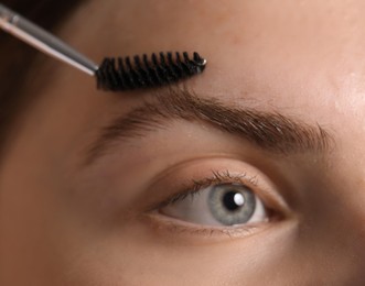Photo of Young woman brushing her eyebrow with spoolie, closeup