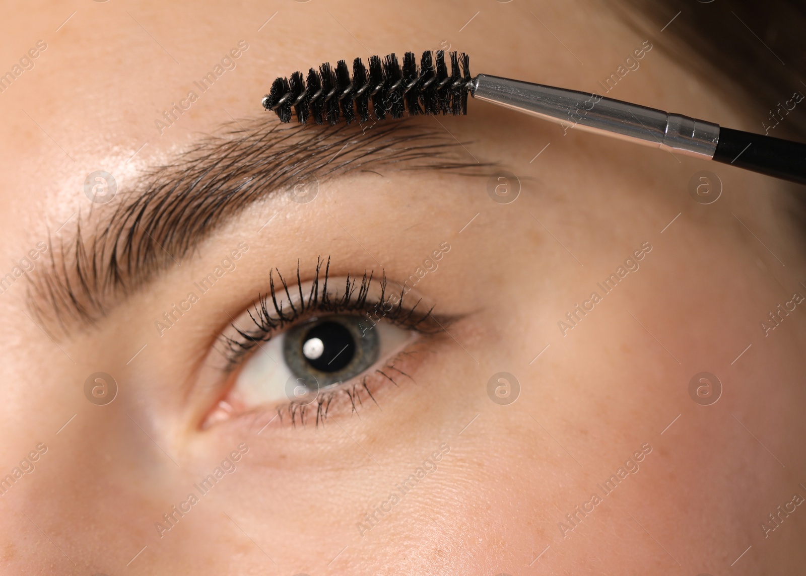 Young woman brushing her eyebrow with spoolie, closeup Photo of Young woman brushing her eyebrow with spoolie, closeup