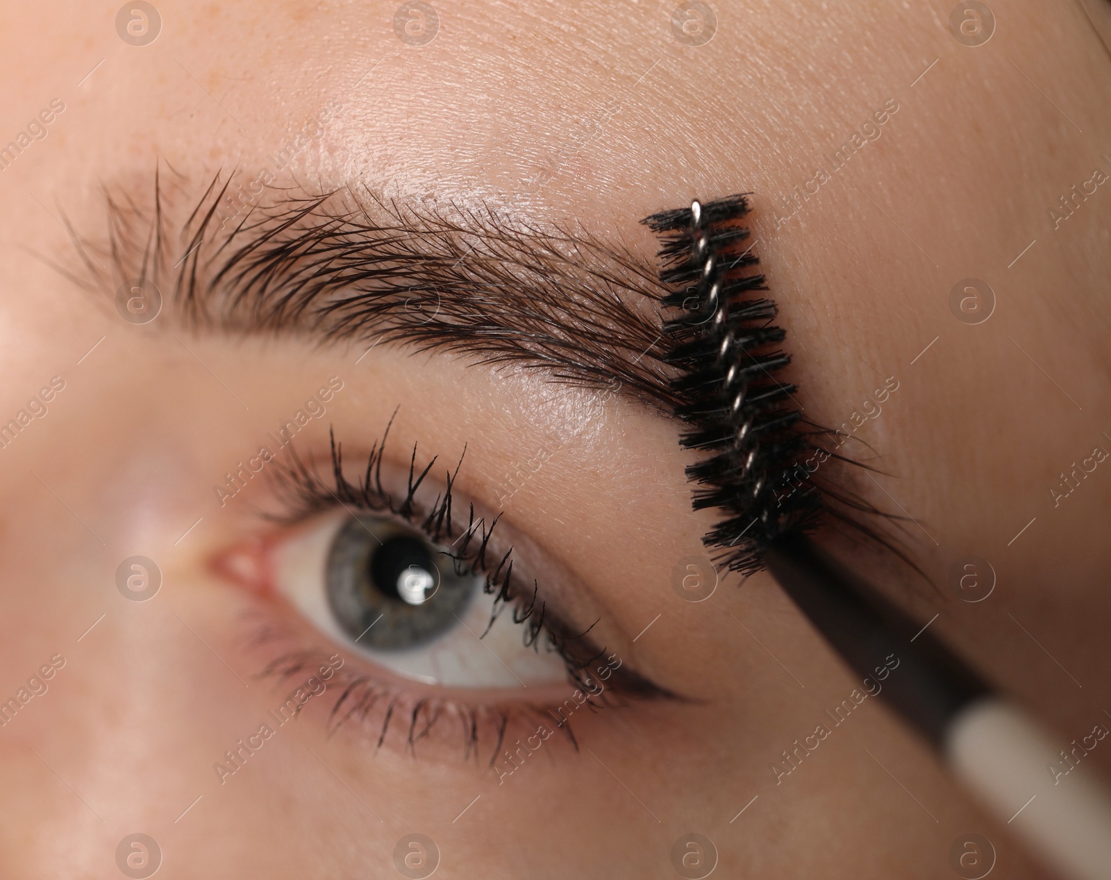 Young woman brushing her eyebrow with spoolie, closeup Photo of Young woman brushing her eyebrow with spoolie, closeup
