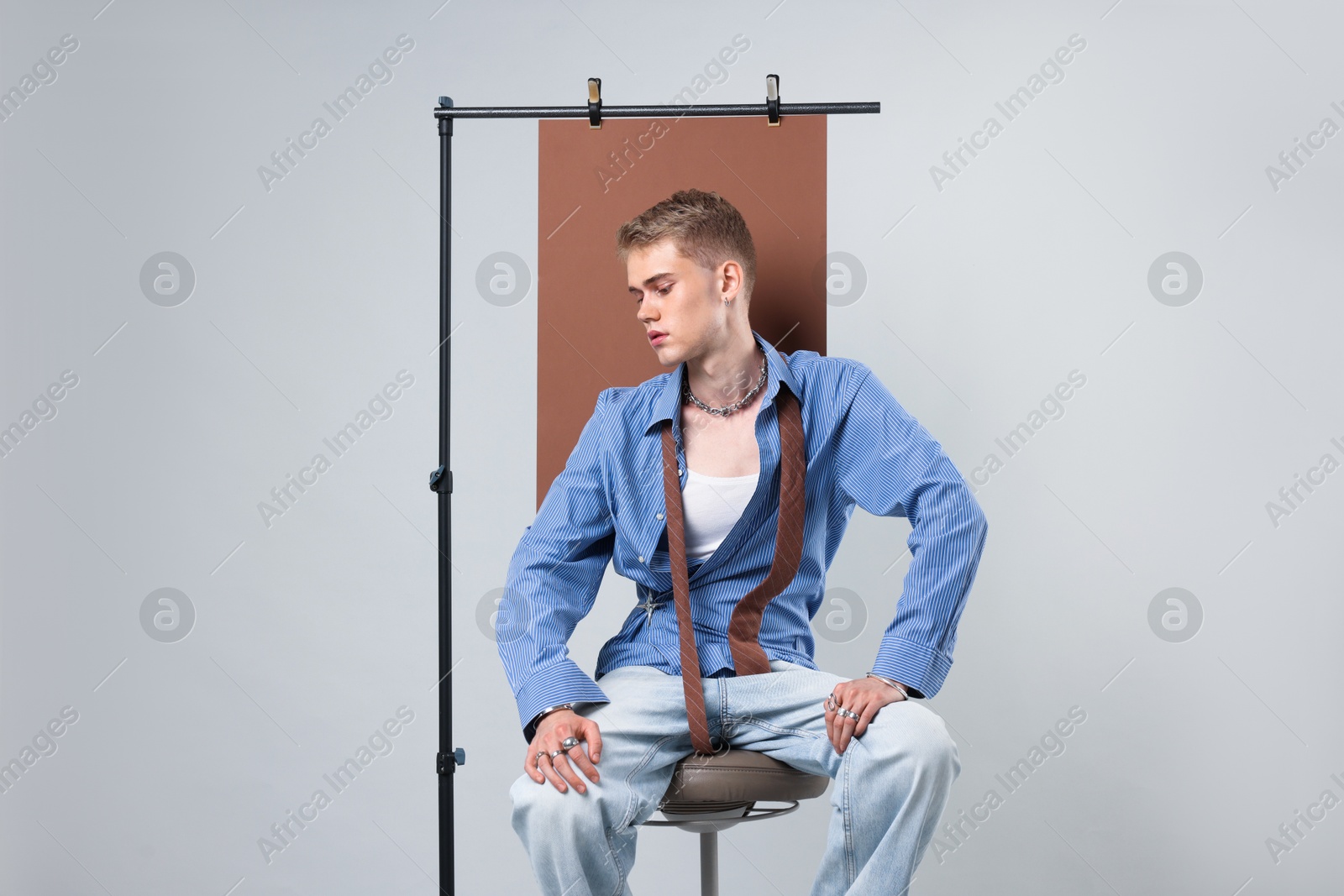 Photo of Handsome young man wearing stylish clothes sitting on chair against light grey background