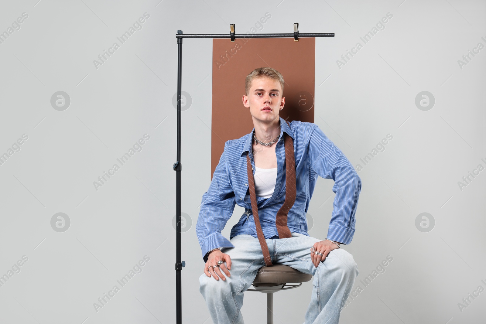 Photo of Handsome young man wearing stylish clothes sitting on chair against light grey background