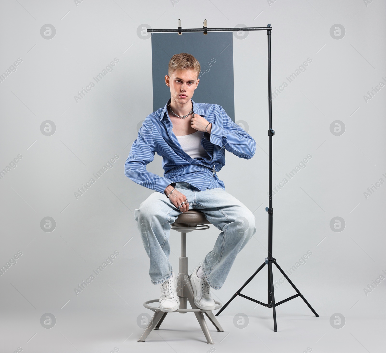 Photo of Handsome young man wearing stylish clothes sitting on chair against light grey background
