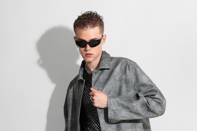 Photo of Handsome young man wearing stylish jacket and sunglasses on white background