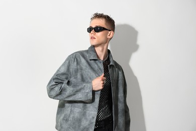 Photo of Handsome young man wearing stylish jacket and sunglasses on white background
