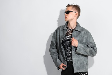 Photo of Handsome young man wearing jacket and sunglasses on white background, space for text