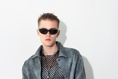 Photo of Handsome young man wearing jacket and sunglasses on white background, space for text