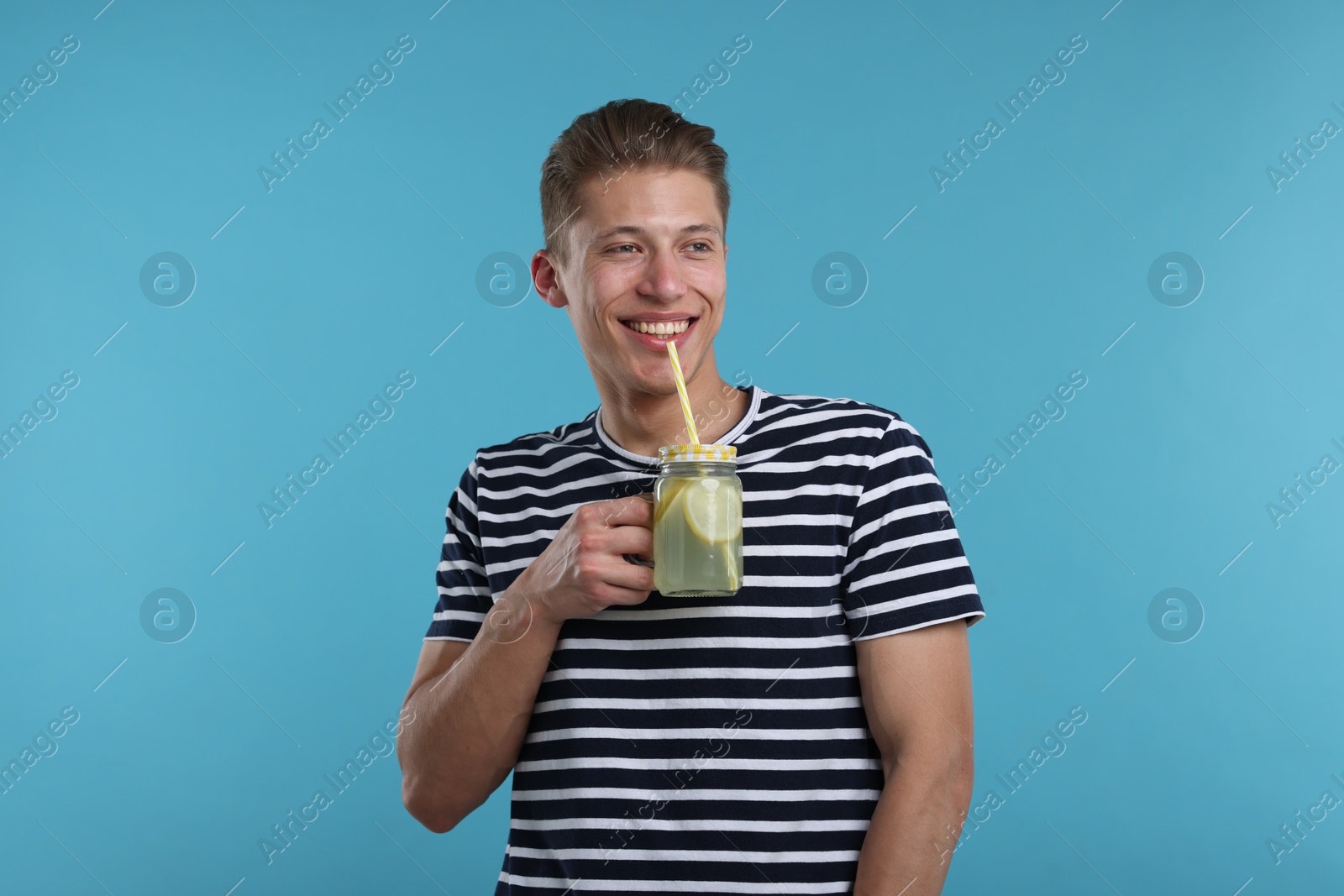 Smiling man drinking lemonade from mason jar on light blue background. Refreshing drink Photo of Smiling man drinking lemonade from mason jar on light blue background. Refreshing drink