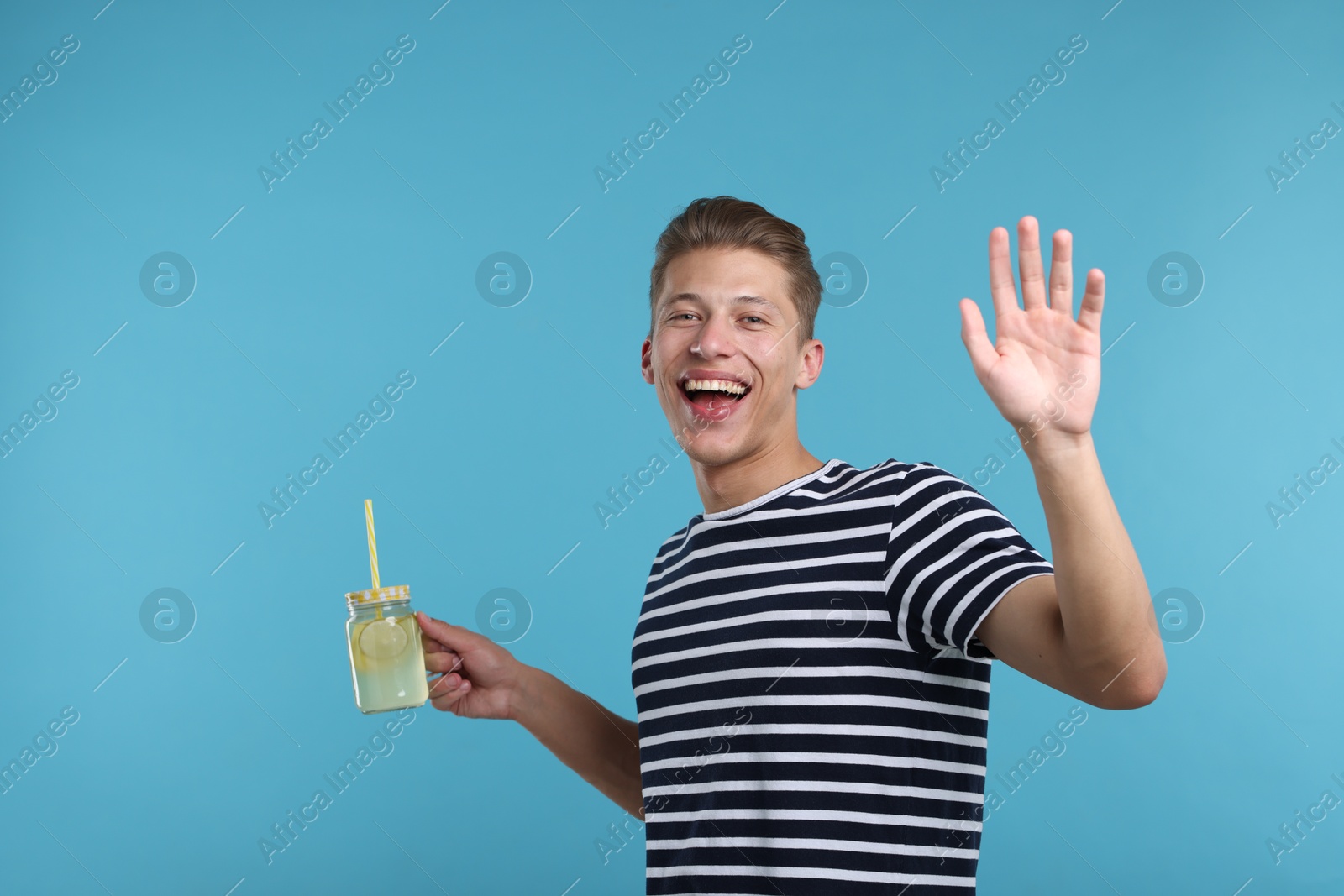 Happy man with mason jar of lemonade on light blue background. Refreshing drink Photo of Happy man with mason jar of lemonade on light blue background. Refreshing drink