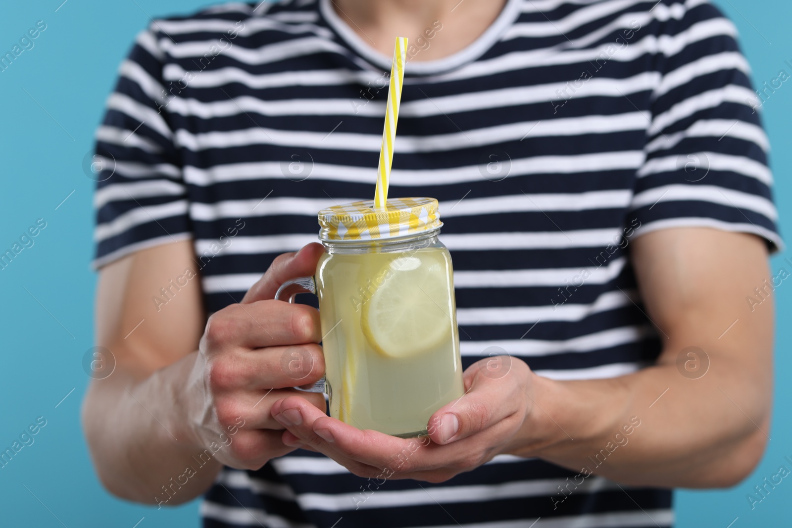 Man with mason jar of lemonade on light blue background, closeup. Refreshing drink Photo of Man with mason jar of lemonade on light blue background, closeup. Refreshing drink