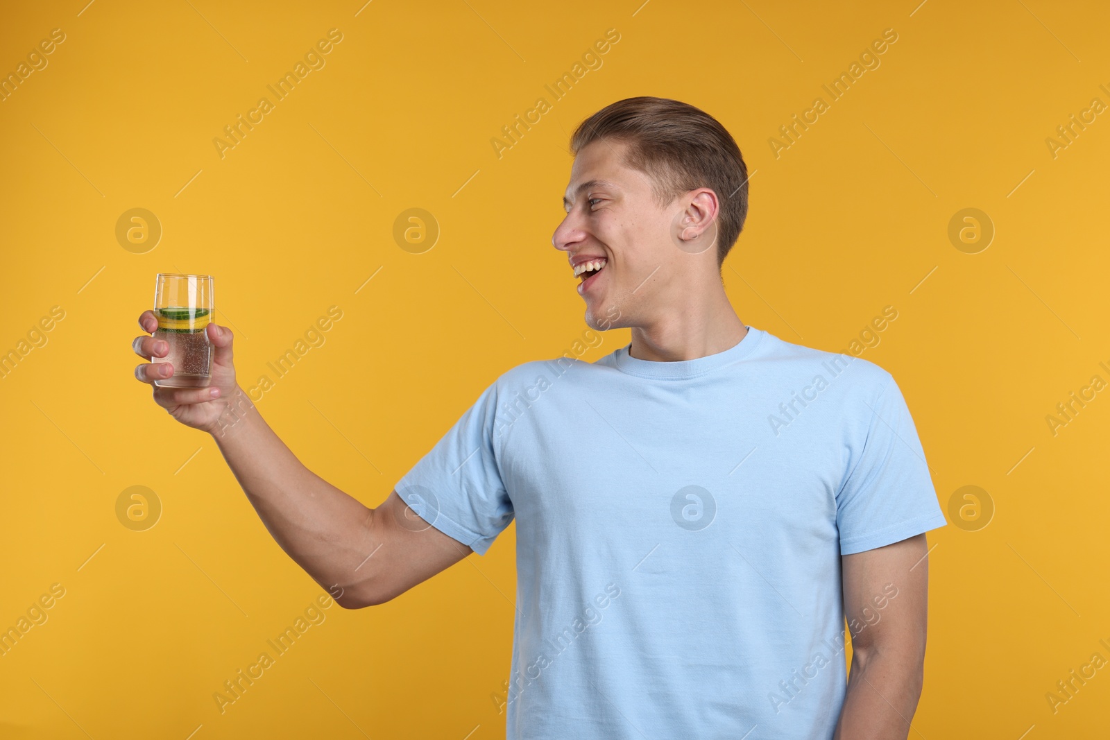 Happy man with glass of refreshing drink on yellow background Photo of Happy man with glass of refreshing drink on yellow background