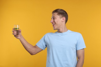 Photo of Happy man with glass of refreshing drink on yellow background