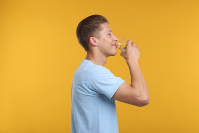 Photo of Man drinking refreshing beverage from glass on yellow background