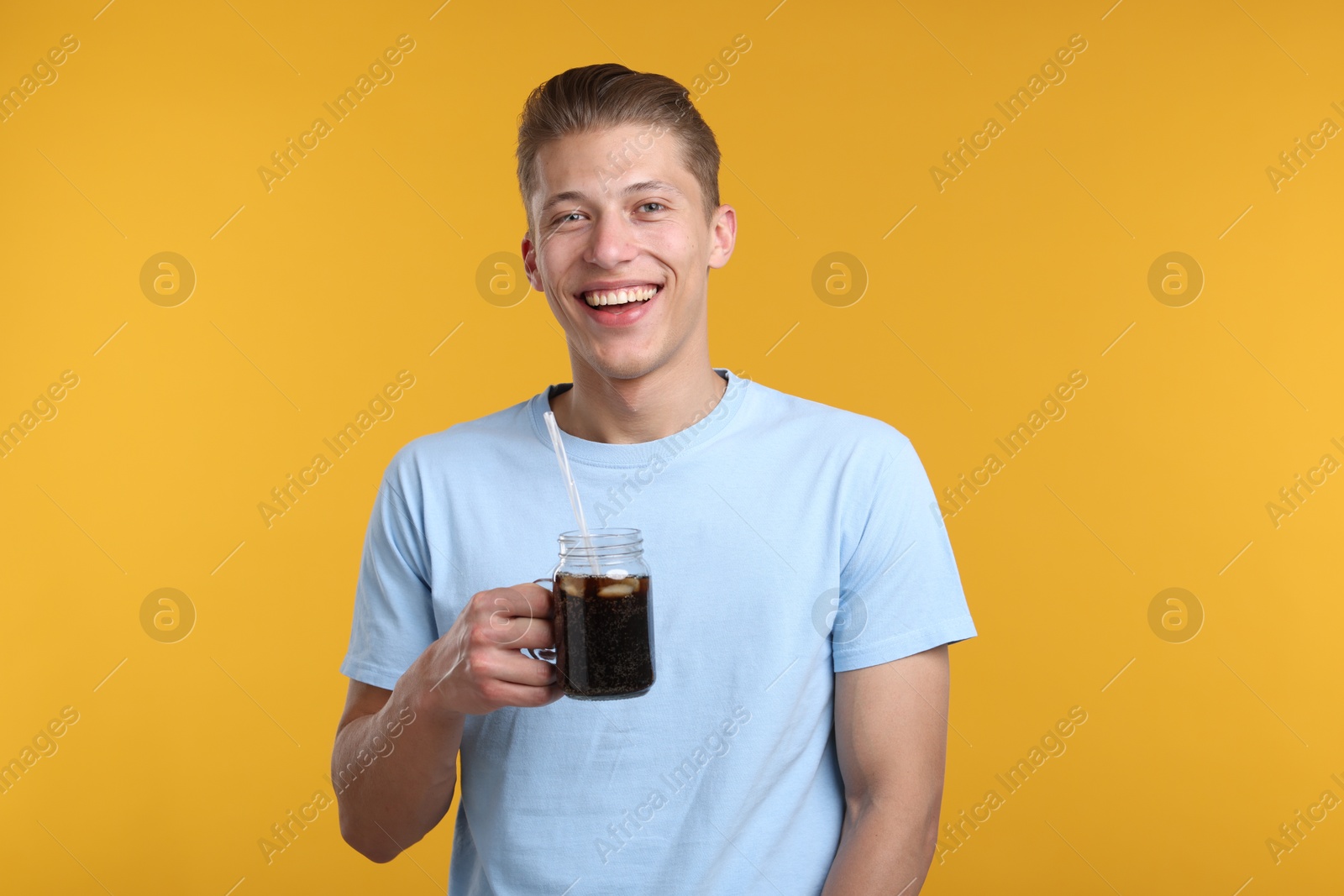Photo of Happy man with mason jar of refreshing soda drink on yellow background