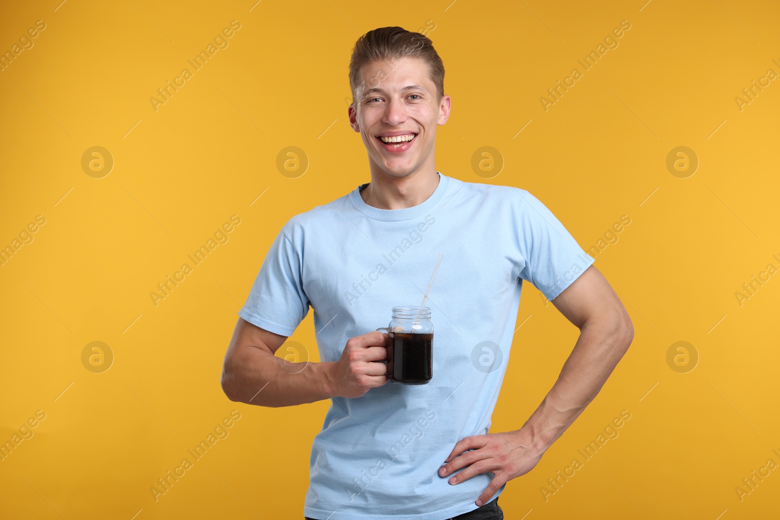 Photo of Happy man with mason jar of refreshing soda drink on yellow background
