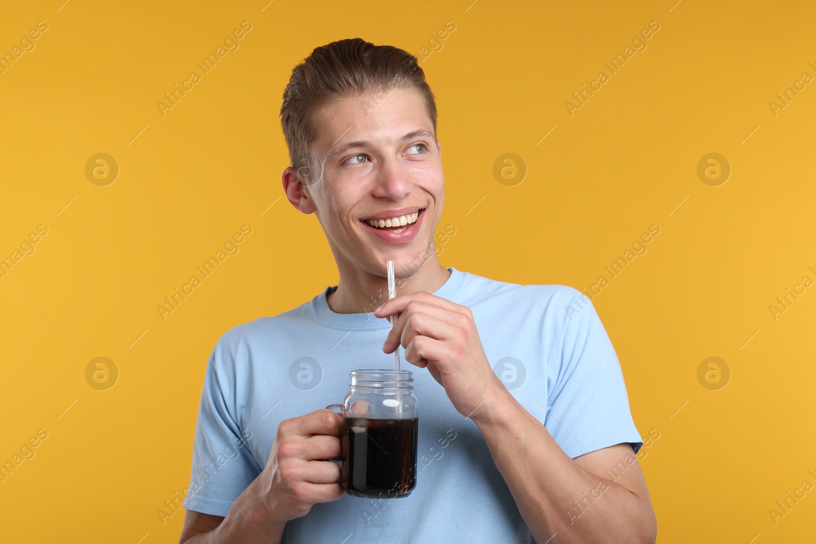 Happy man with mason jar of refreshing soda drink on yellow background Photo of Happy man with mason jar of refreshing soda drink on yellow background
