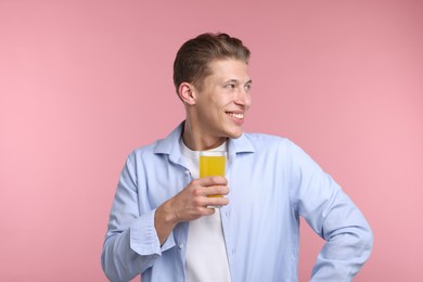 Photo of Happy man with glass of orange juice on pink background. Refreshing drink