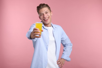 Photo of Happy man with glass of orange juice on pink background. Refreshing drink