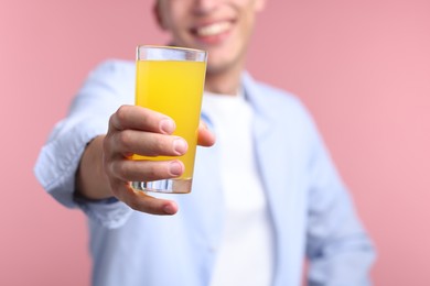 Photo of Happy man with glass of orange juice on pink background, closeup. Refreshing drink