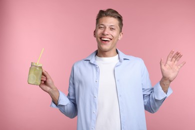Photo of Happy man with mason jar of lemonade on pink background. Refreshing drink