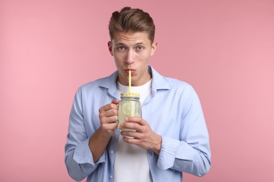 Photo of Man drinking lemonade from mason jar on pink background. Refreshing drink