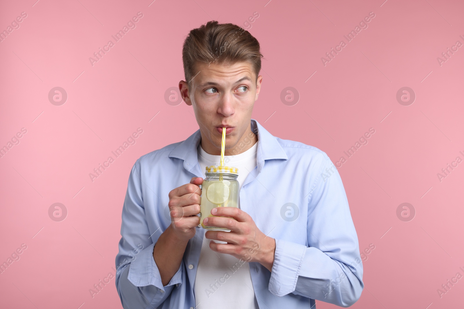 Man drinking lemonade from mason jar on pink background. Refreshing drink Photo of Man drinking lemonade from mason jar on pink background. Refreshing drink