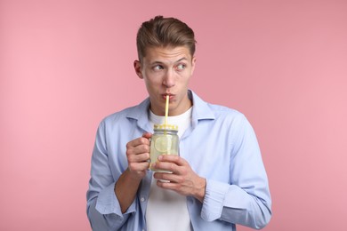 Photo of Man drinking lemonade from mason jar on pink background. Refreshing drink