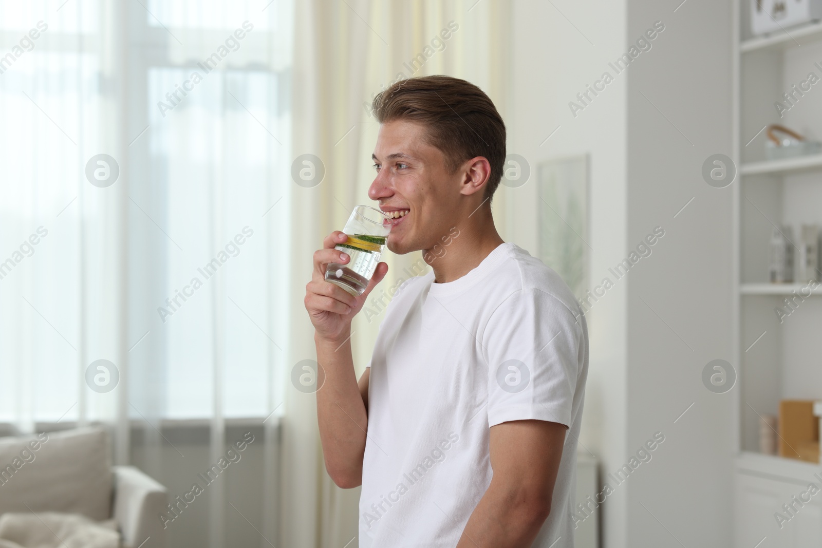 Happy man drinking healthy beverage from glass at home. Refreshing drink Photo of Happy man drinking healthy beverage from glass at home. Refreshing drink