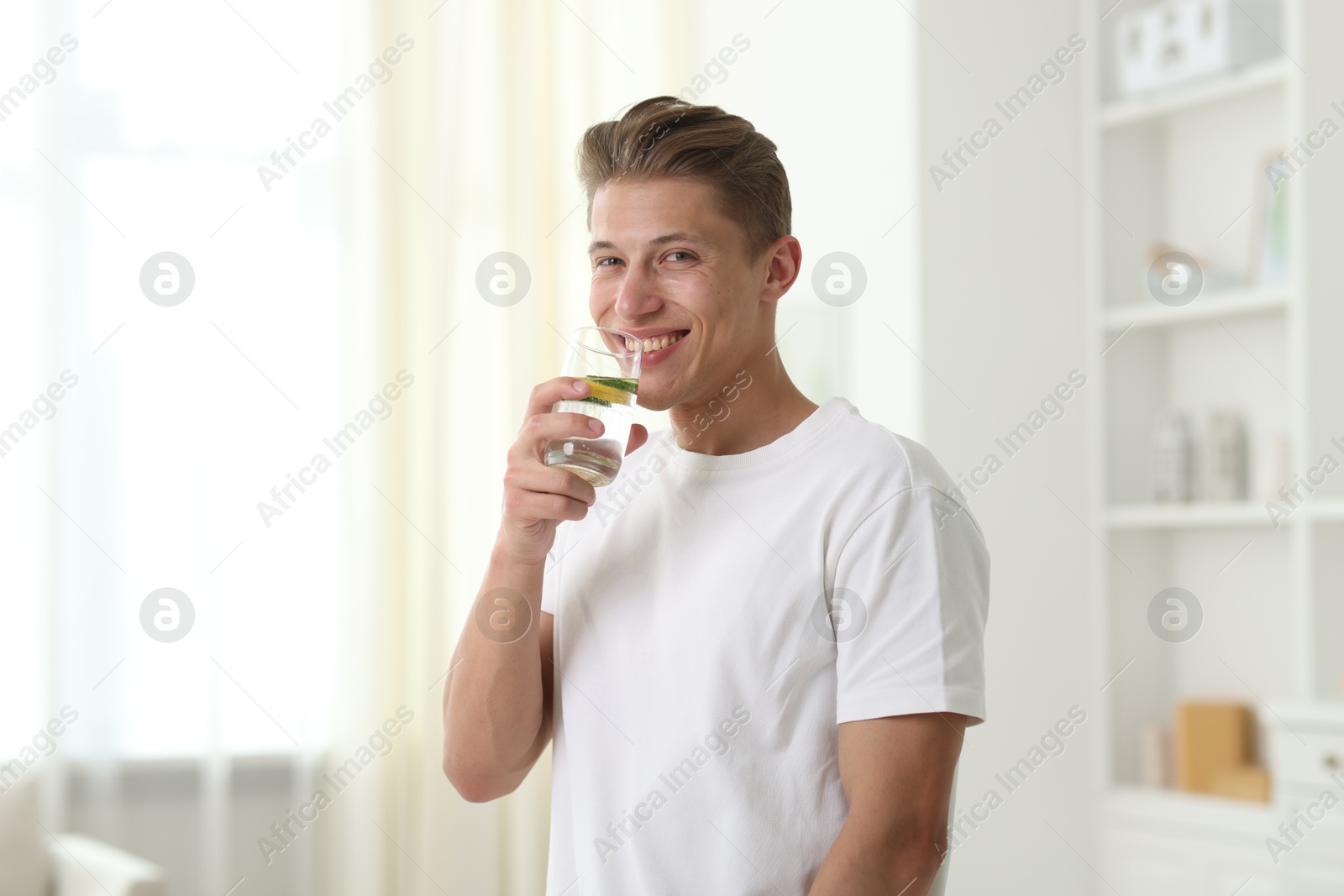Happy man drinking healthy beverage from glass at home. Refreshing drink Photo of Happy man drinking healthy beverage from glass at home. Refreshing drink