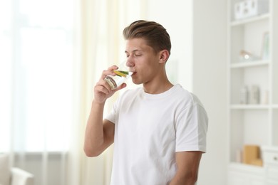 Photo of Man drinking healthy beverage from glass at home. Refreshing drink