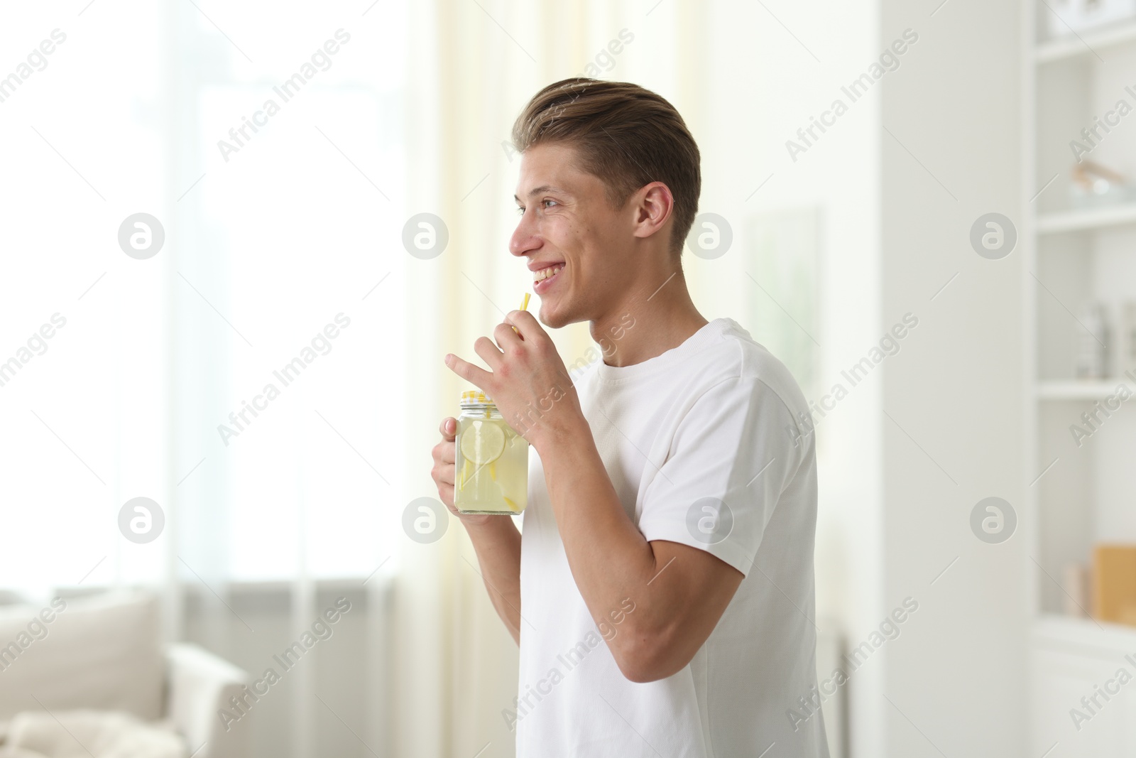 Happy man with mason jar of lemonade at home. Refreshing drink Photo of Happy man with mason jar of lemonade at home. Refreshing drink