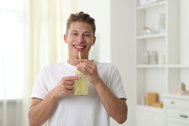 Photo of Happy man with mason jar of lemonade at home. Refreshing drink