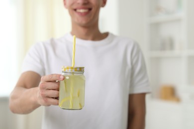 Photo of Happy man with mason jar of lemonade at home, closeup. Refreshing drink