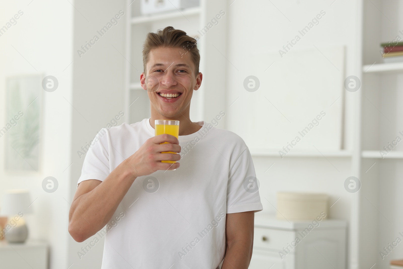 Smiling man with glass of orange juice at home. Refreshing drink Photo of Smiling man with glass of orange juice at home. Refreshing drink