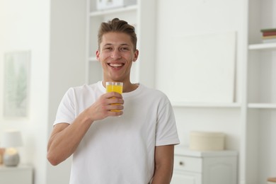 Photo of Smiling man with glass of orange juice at home. Refreshing drink