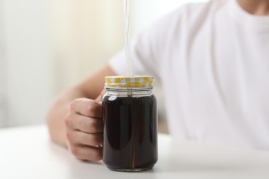 Photo of Man with mason jar of refreshing soda drink at white table indoors, closeup