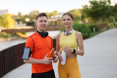 Photo of Portrait of happy couple with thermo bottles after morning exercises outdoors
