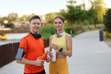 Photo of Portrait of happy couple with thermo bottles after morning exercises outdoors