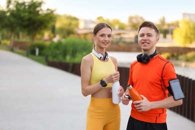 Photo of Portrait of happy couple with thermo bottles after morning exercises outdoors. Space for text