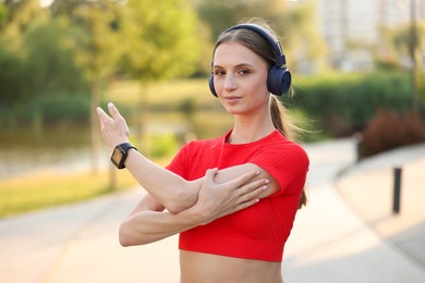 Photo of Young sportswoman in headphones doing morning exercise outdoors. Healthy lifestyle