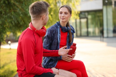 Photo of Couple resting on bench after morning exercises outdoors