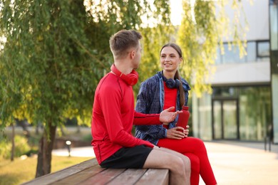 Photo of Happy couple resting on bench after morning exercises outdoors