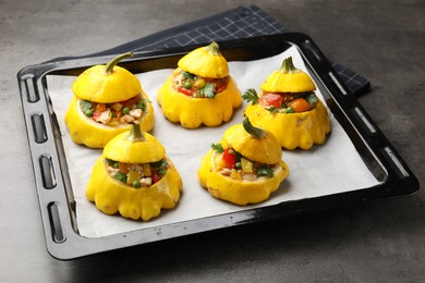 Photo of Tasty stuffed pattypan squashes on dark textured table, closeup
