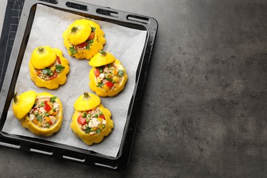 Photo of Tasty stuffed pattypan squashes on dark textured table, top view. Space for text
