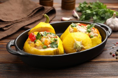 Photo of Tasty stuffed pattypan squashes in baking dish on wooden table, closeup